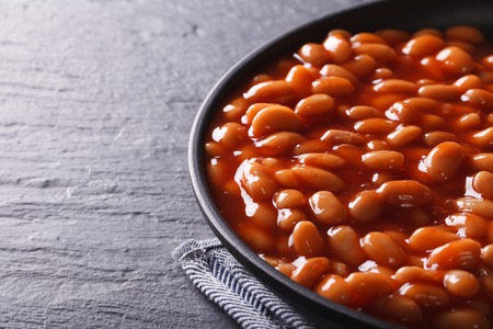 beans in tomato sauce in a black bowl close-up horizontalの写真素材