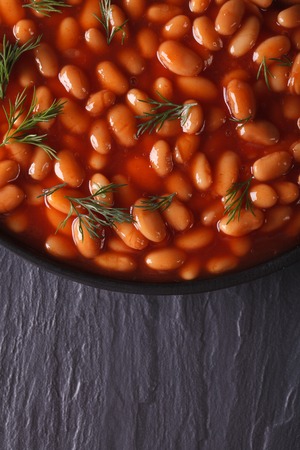 white beans in tomato sauce with dill in a black bowl close-upの写真素材