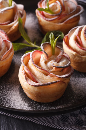 healthy food: apple pie in the form of roses on a black plate macro. vertical