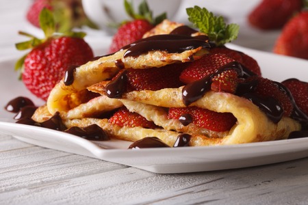 Beautiful crepes with fresh strawberries and chocolate topping close-up on a plate. horizontalの写真素材