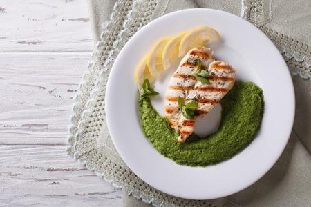 Grilled chicken and a side dish of green peas on a white plate. horizontal view from aboveの写真素材
