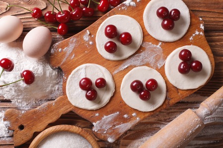 cooking dumplings with cherries close-up on a wooden table. Horiozntal top viewの写真素材