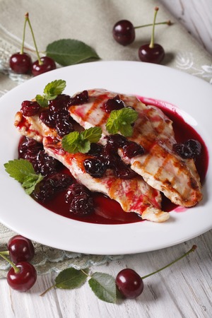 Grilled chicken with cherry sauce and mint on a white plate close up. verticalの写真素材