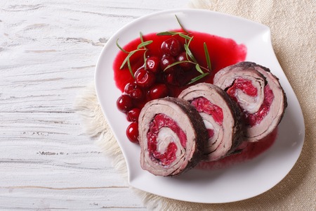 Beef roll stuffed with cherries close-up on a plate and sauce. horizontal view from aboveの写真素材
