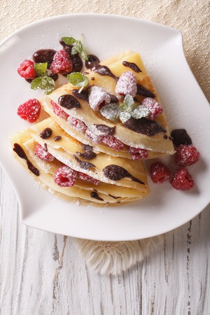 raspberry crepes with chocolate and mint close-up on a plate. Vertical view from aboveの写真素材