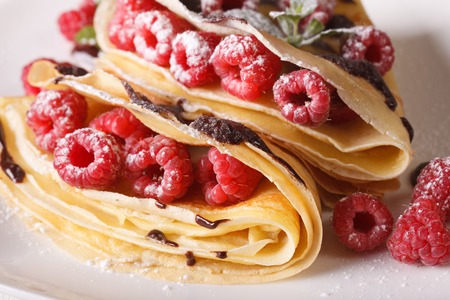 Beautiful raspberry crepes with chocolate frosting macro on a plateの写真素材