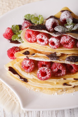 Beautiful crepes with fresh raspberries and chocolate close-up on a plate. verticalの写真素材