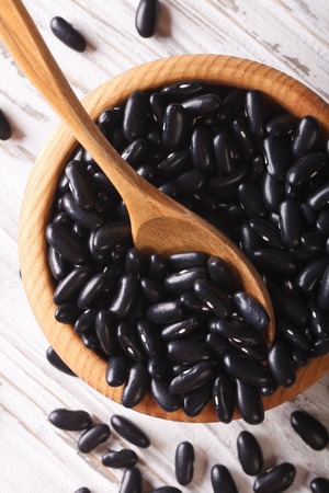 raw black beans in a wooden bowl on the table close-up. vertical top viewの写真素材