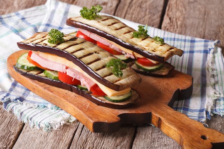 Aubergine sandwiches with fresh vegetables, ham and cheese on the table. horizontalの写真素材