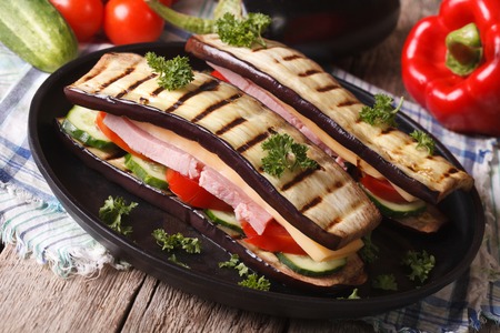 Unusual aubergine sandwich with vegetables, ham and cheese close-up on a plate. horizontalの写真素材