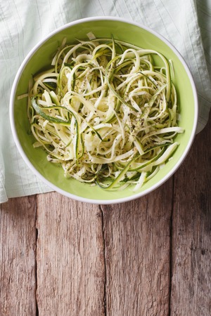 Useful raw zucchini pasta in a bowl close up on the table. vertical top viewの写真素材