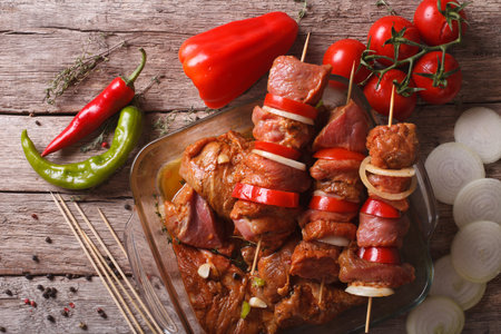 raw kebab with vegetables in a spicy marinade on skewers on the table. horizontal top viewの写真素材