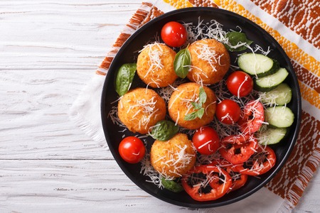 Italian arancini rice balls with cheese and fresh vegetables on the plate. horizontal top viewの写真素材