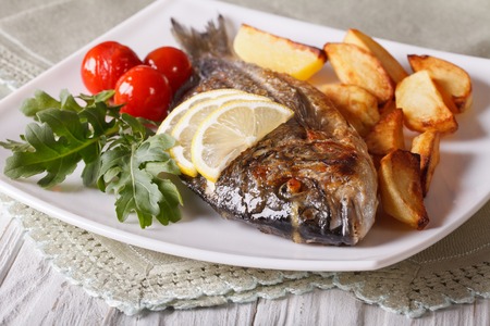 Grilled dorado fish with fried potatoes on the plate closeup. horizontalの写真素材