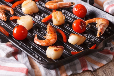 Sea scallops and shrimp are fried on a grill pan close-up. Horizontalの写真素材