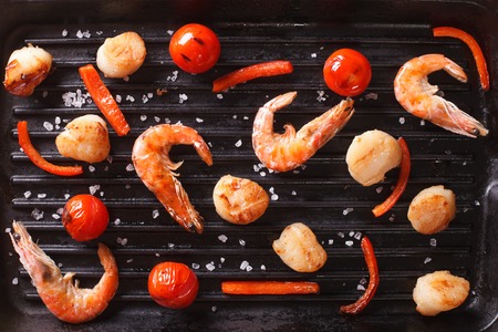 Scallops, shrimp and vegetables on grill close-up. background horizontal view from aboveの写真素材