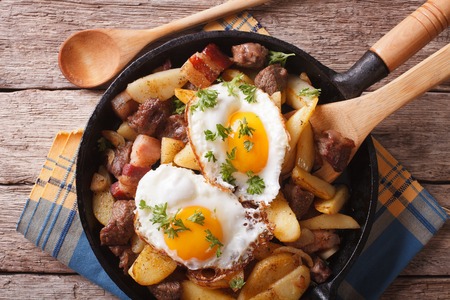 Tyrolean fried potatoes with meat, bacon and eggs in a pan close-up. horizontal top viewの写真素材