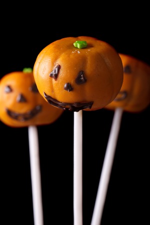 Halloween pumpkin cake pops isolated on a black background. Verticalの写真素材