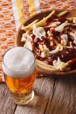 Canadian food: beer and fries with sauce close-up on the table