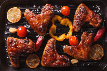 Chicken wings with vegetables in a grill closeup. horizontal view from above