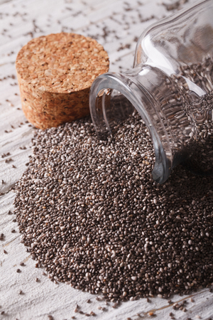 Chia seeds spill out of glass jar on the table close-up.の写真素材