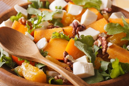 Healthy salad with persimmons, walnuts, arugula, cheese and oranges macro.の写真素材
