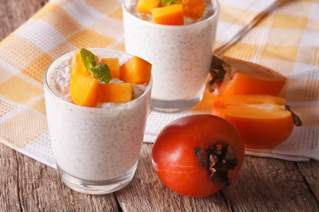 Delicious breakfast: chia seed pudding and persimmon close up in a glass on the table.の写真素材