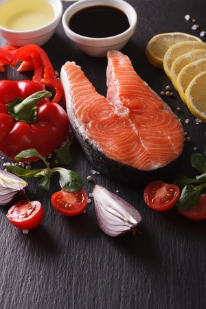 Raw salmon steak and ingredients on a slate board closeup. verticalの写真素材