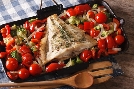 flatfish with vegetables close-up on a frying pan on the table. Horizontal