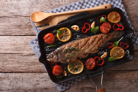 trout with vegetables on a grill pan on the table. horizontal view from aboveの写真素材