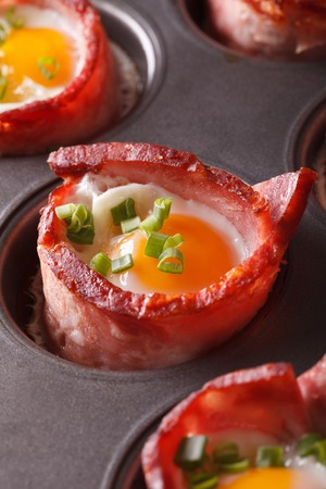 Baked eggs wrapped in crispy bacon macro in baking dish. verticalの写真素材