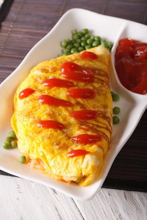 Japanese omelet stuffed with rice and chicken close-up on a plate. verticalの写真素材