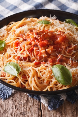 Amatriciana Spaghetti with cheese and basil close-up on a plate on the table. verticalの写真素材