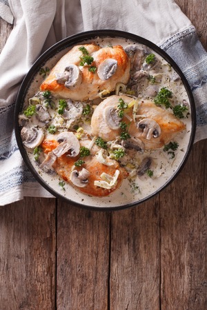 Chicken breast with mushrooms in cream sauce on a plate on the table. vertical top viewの写真素材