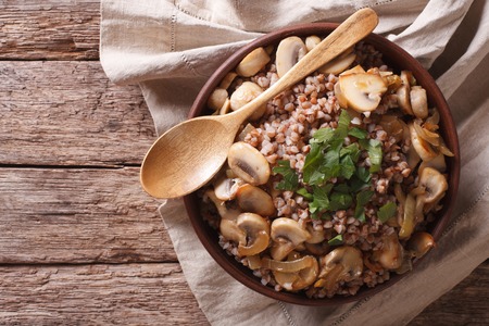 Buckwheat with roasted mushrooms and onions in a bowl on the table. Horizontal view from aboveの写真素材