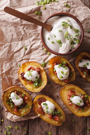Rustic potato skins with cheese, bacon and sour cream close-up on the table. vertical view from aboveの写真素材