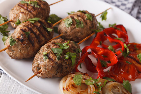 Kofta kebab with grilled vegetables on a plate close-up on the table. horizontal