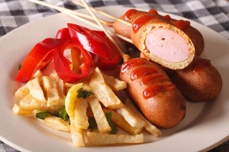 Corn dog with fries and vegetables on a plate close-up on the table. Horizontalの写真素材