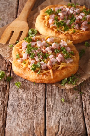 langos deep fried with cheese and ham close-up on the table. verticalの写真素材
