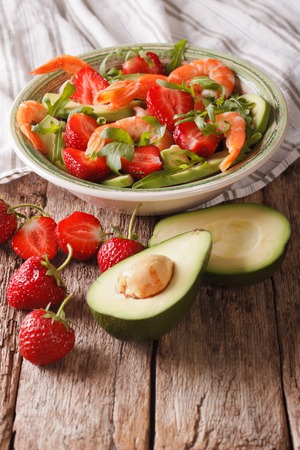 Fresh salad with strawberries, avocado, shrimp and arugula close-up on a plate. Verticalの写真素材