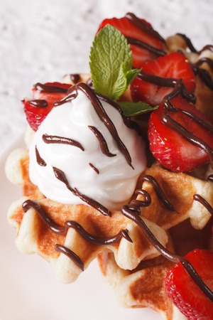 Tasty waffles with strawberries, whipped cream and chocolate frosting macro. verticalの写真素材
