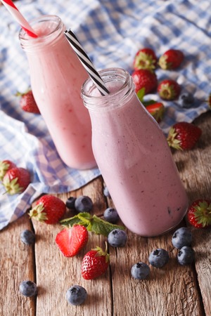 smoothie with strawberries and blueberries in bottles close-up on the table. verticalの写真素材