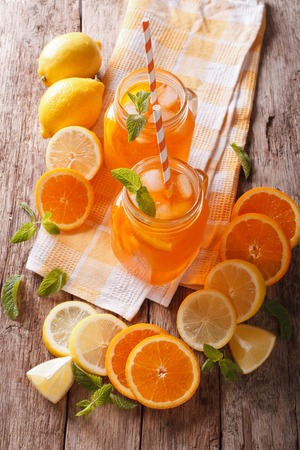 cold orange drink with lemon, mint and ice close-up on the table. Vertical view from aboveの写真素材