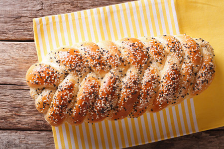 Freshly baked loaf of braided, with sesame seeds close up on the table. horizontal view from above