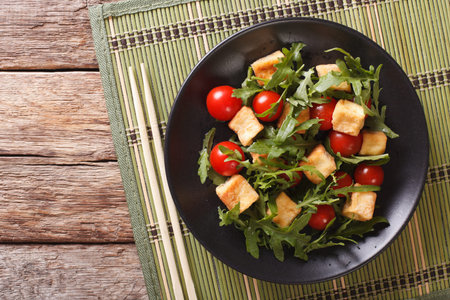 Asian salad with fried tofu, tomatoes and arugula close-up on a plate. Horizontal view from aboveの写真素材