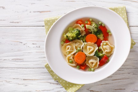 Vegetable soup with tortellini in a plate close-up. Horizontal view from aboveの写真素材