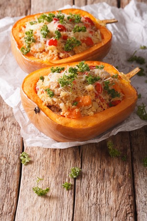 half baked pumpkin filled with an couscous, meat, vegetables and cheese close-up on the table. verticalの写真素材
