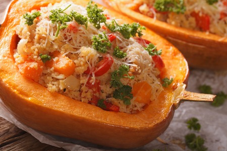 Baked pumpkin stuffed with couscous, meat and vegetables macro on the table. horizontalの写真素材