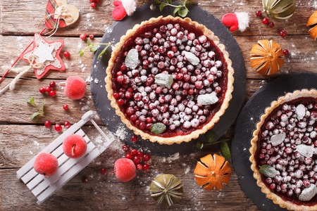 Freshly baked Christmas cranberry tart with icing sugar and festive decoration close-up on the table. horizontal view from aboveの写真素材