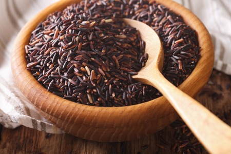 Natural Foods: Raw wild black rice macro in a wooden bowl. Horizontal backgroundの写真素材